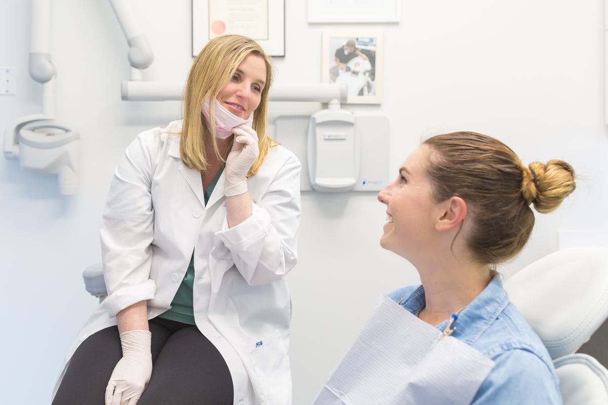 Odontóloga conversando con una paciente en la consulta dental